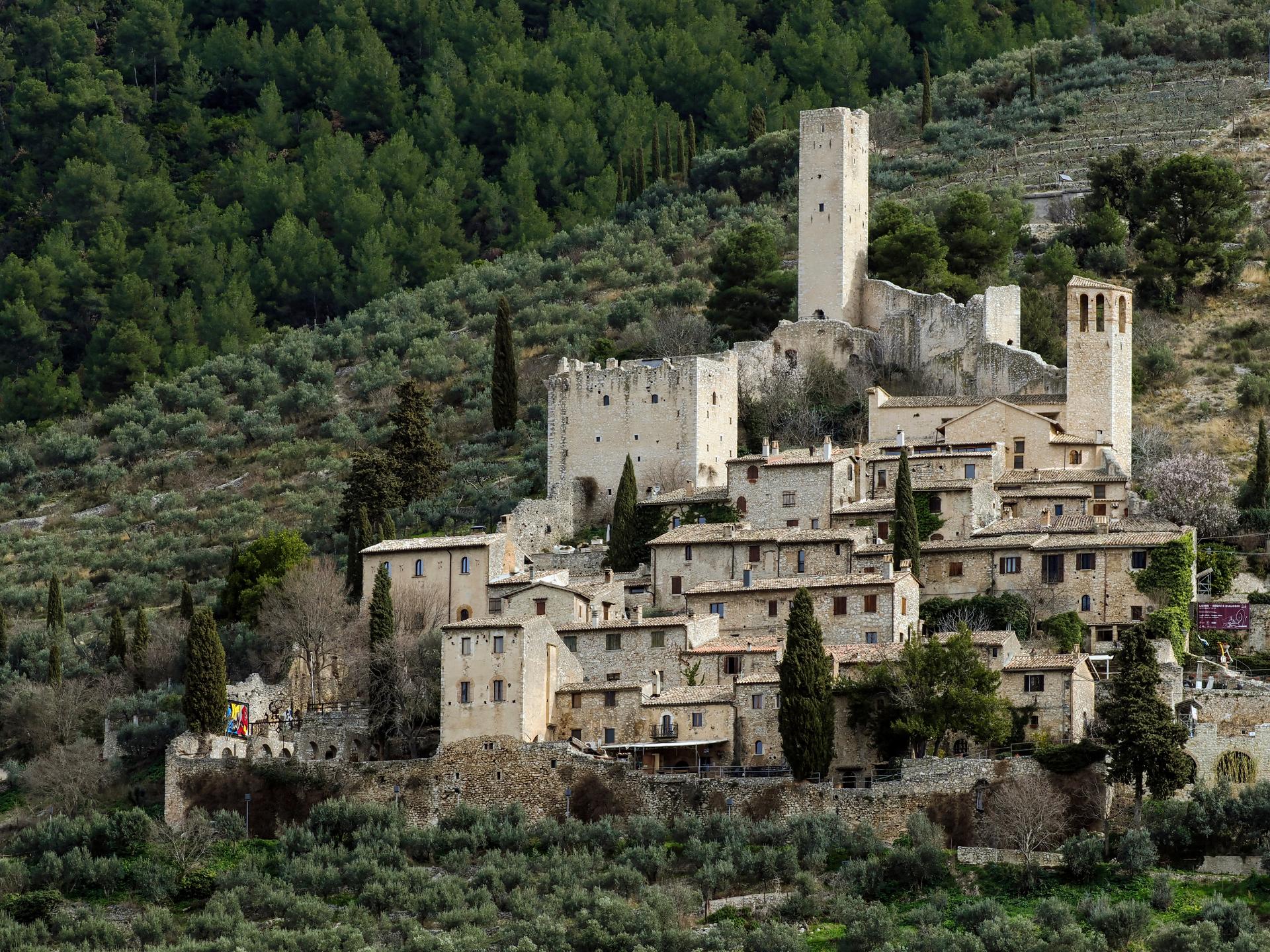 Castle of Pissignano Alto, with medieval towers and stone houses nestled among olive groves and wooded hills